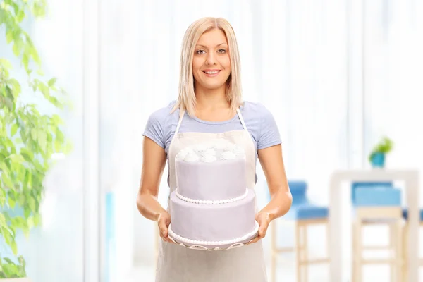 Junge blonde Hausfrau hält Kuchen — Stockfoto