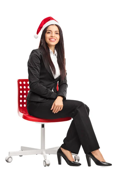 Businesswoman with Santa hat sitting on a chair — Φωτογραφία Αρχείου