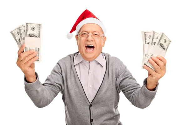 Senior man with Santa hat holding money — Stok fotoğraf