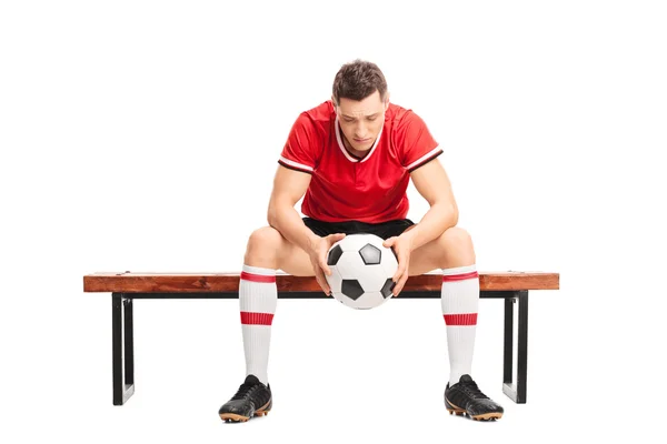 Sad football player sitting on a bench — Stock Photo, Image