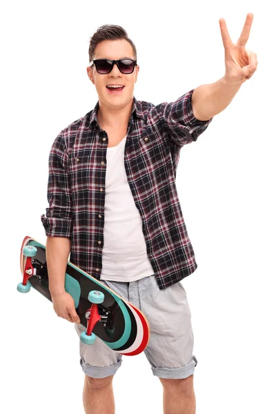 Skater with skateboard making a peace sign — Zdjęcie stockowe