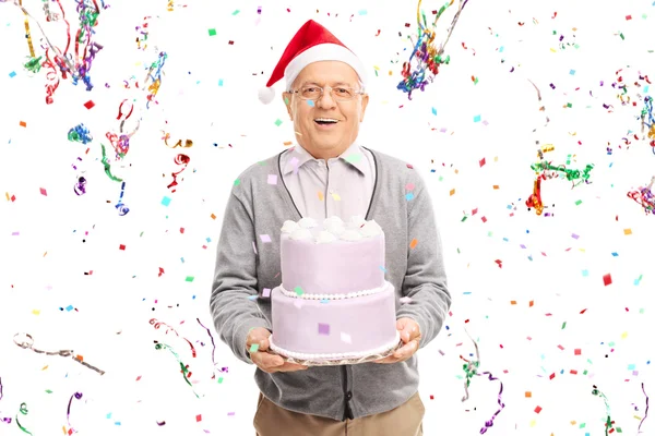 Seniorchef mit Weihnachtsmütze hält Kuchen in der Hand — Stockfoto