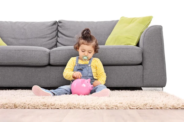 Baby girl putting a coin into a piggybank — Stock Photo, Image