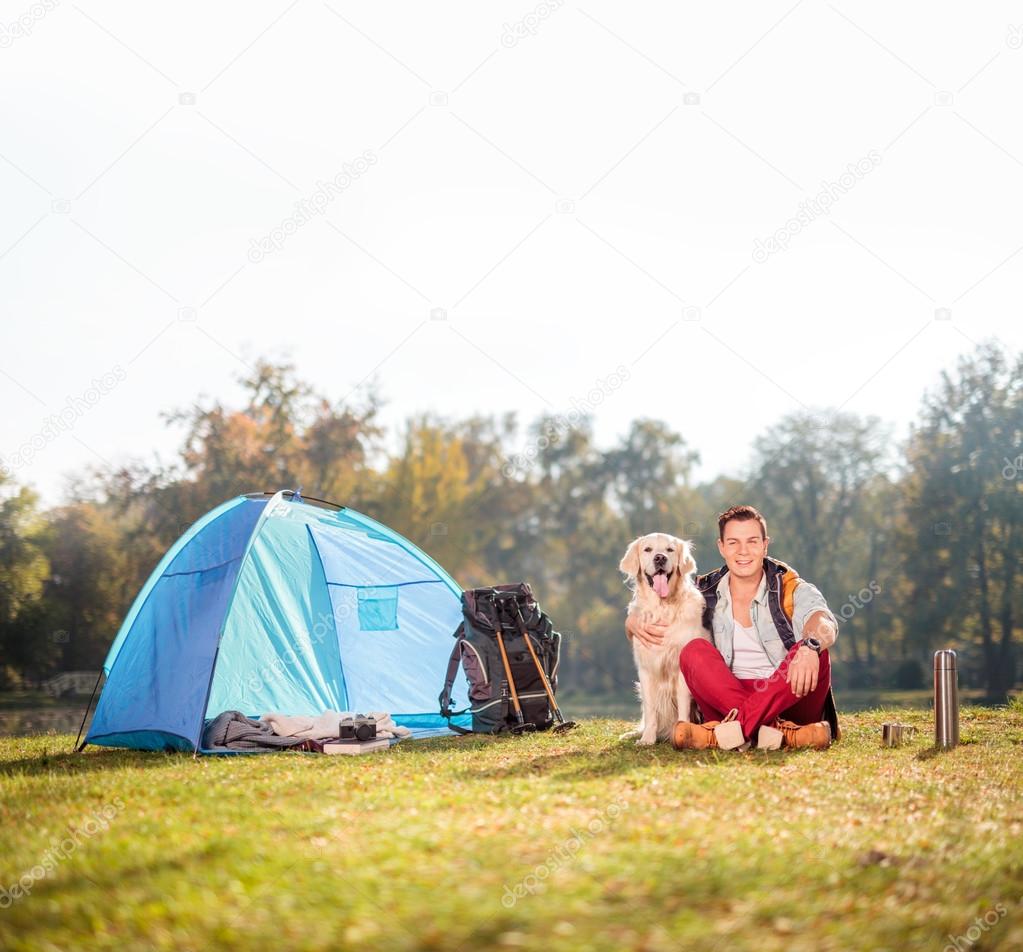Camper on grass hugging a dog