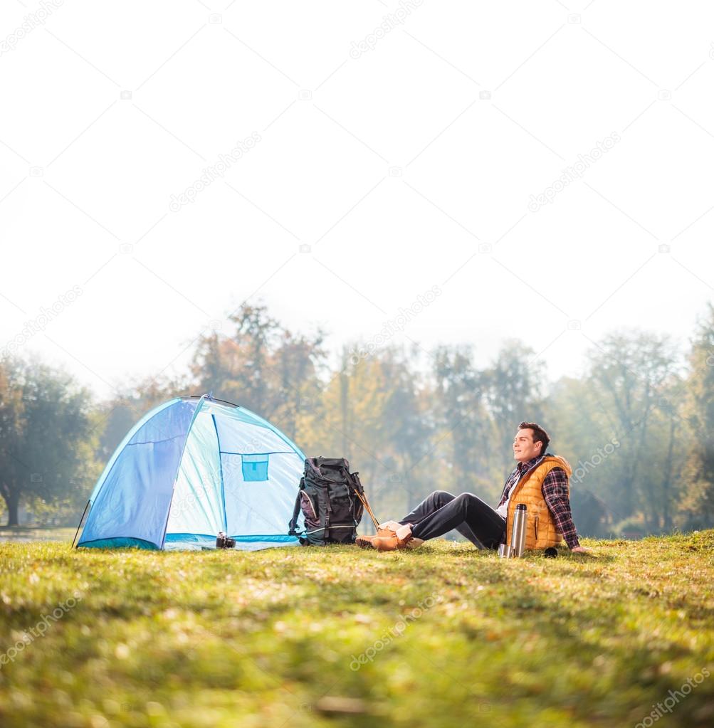 hiker sitting next to a blue tent