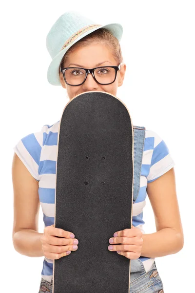 Хипстерская девушка прячет скейтборд и улыбается — стоковое фото