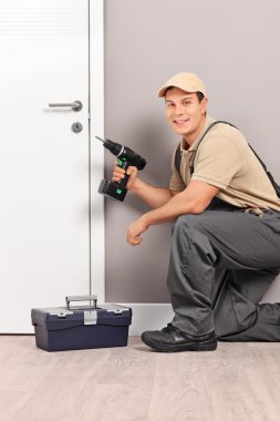 worker installing a door with a screwing drill clipart