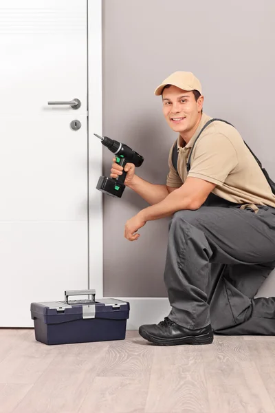 Trabalhador instalando uma porta com uma broca de aparafusamento — Fotografia de Stock