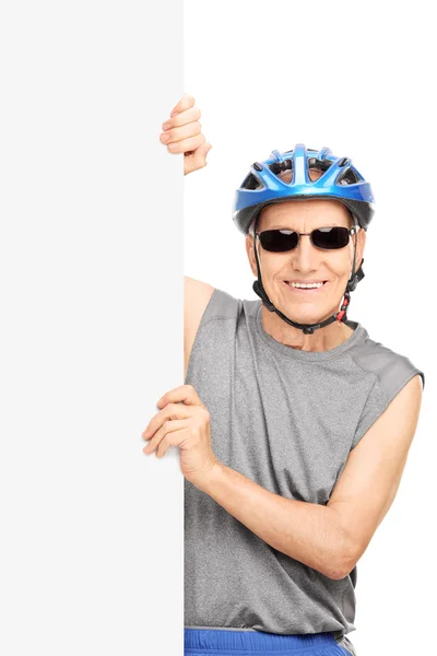 Senior cyclist posing behind a signboard — Stock Photo, Image