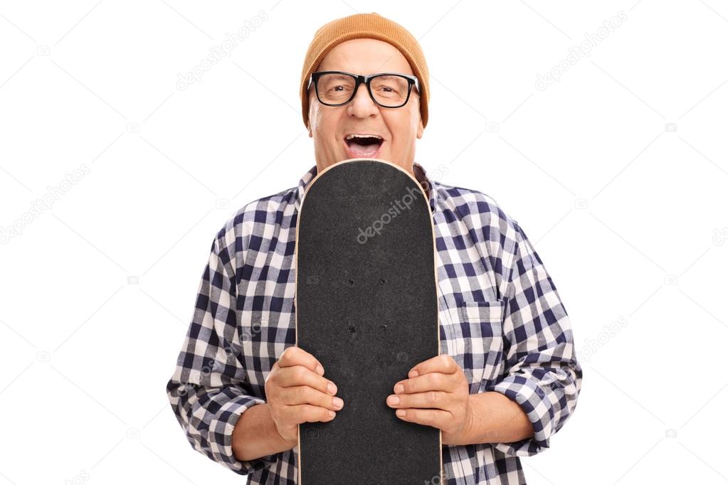 Joyful senior skater holding a skateboard 