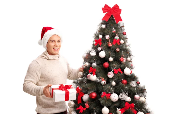 Hombre de pie junto a un árbol de Navidad con regalo —  Fotos de Stock