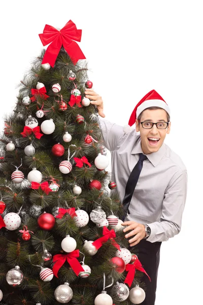 Guy with Santa hat standing by a Christmas tree Stock Image