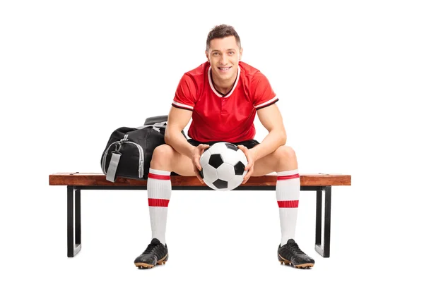 Young football player sitting on a bench — Stock Photo, Image