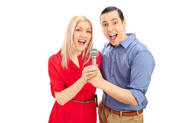 Young joyful couple singing on microphone — Stock Photo, Image