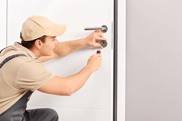 Cerrajero instalando una cerradura en una puerta — Foto de Stock