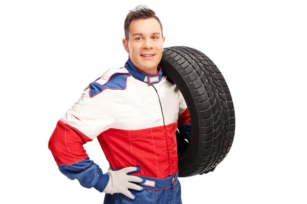 Automobilový závodník nesoucí pneumatiku na rameni — Stock fotografie