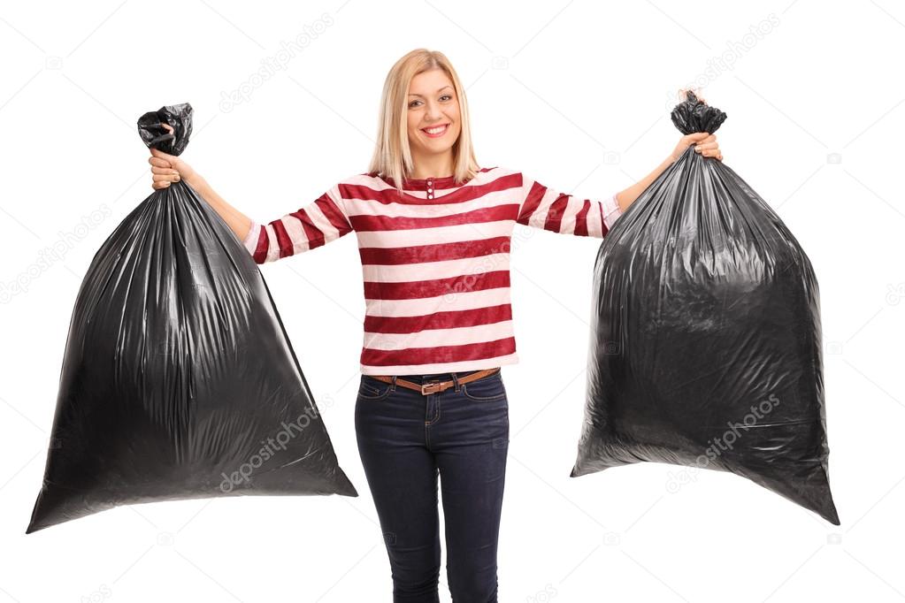 Cheerful woman holding trash bags