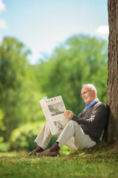 Senior gentleman reading a newspaper in park — Stockfoto