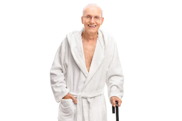 Senior man in a bathrobe holding a cane — ストック写真