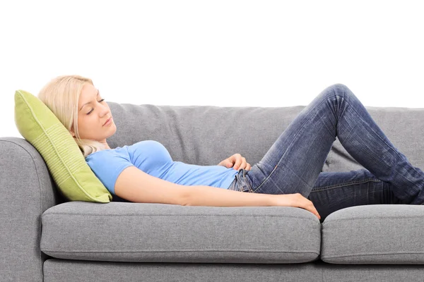 Junge Frau schläft auf einer grauen Couch — Stockfoto