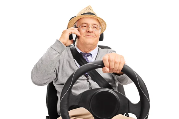 Старший мужчина за рулем и разговаривает по телефону — стоковое фото