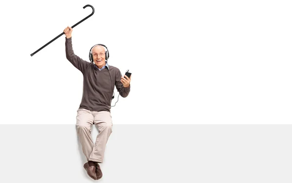 Äldre man lyssnar på musik i hörlurar — Stockfoto