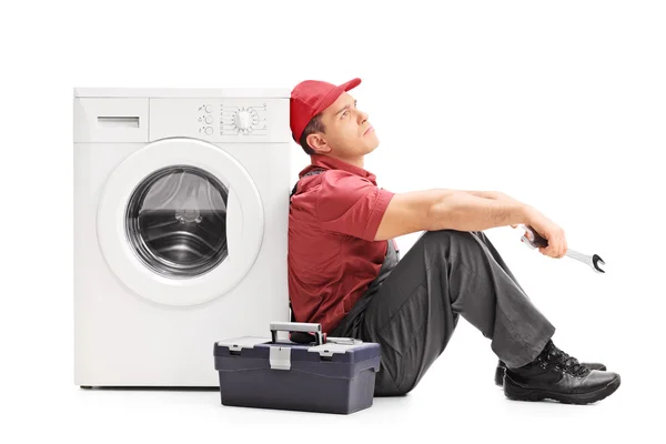 Plumber sitting by a washing machine — Stock Photo, Image