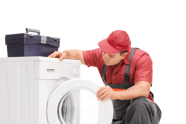 Encanador jovem olhando para uma máquina de lavar roupa — Fotografia de Stock