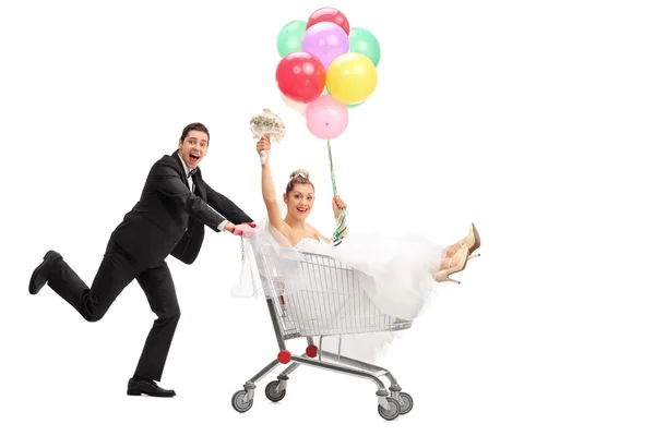 Groom pushing the bride in a shopping cart — Stock Photo, Image
