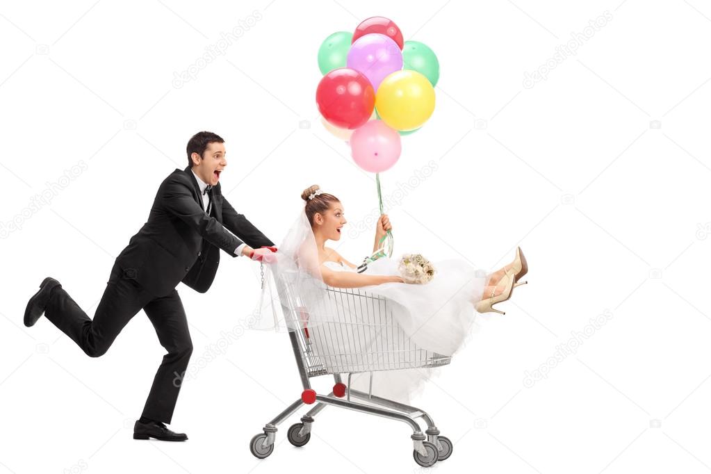 Newlywed couple driving in a shopping cart 
