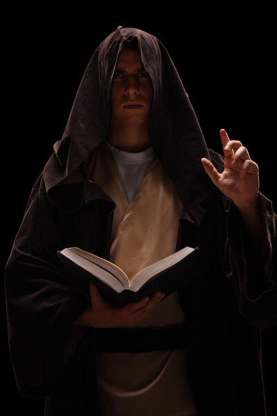 Таинственный монах держит в руках книгу и проповедует
 