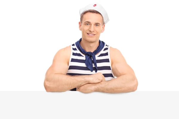 Muscular sailor standing behind a signboard — Stock Photo, Image