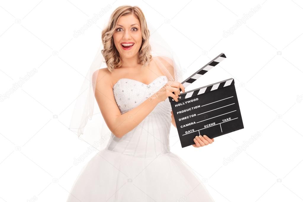 Joyful bride holding a movie clapperboard 