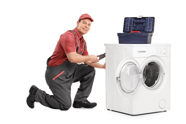 Jovem reparador fixando uma máquina de lavar roupa — Fotografia de Stock