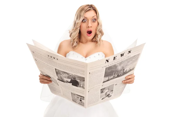 Surprised young bride reading a newspaper — Stock Photo, Image