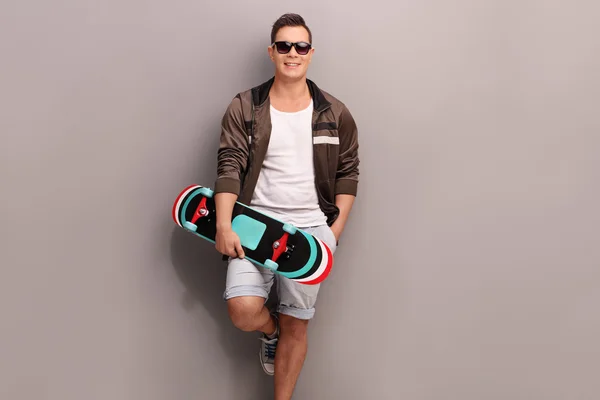 Joven patinador masculino sosteniendo un monopatín — Foto de Stock
