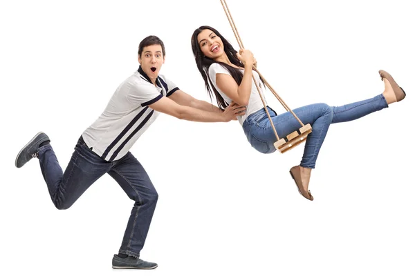Man pushing his girlfriend on a swing — Stock Photo, Image