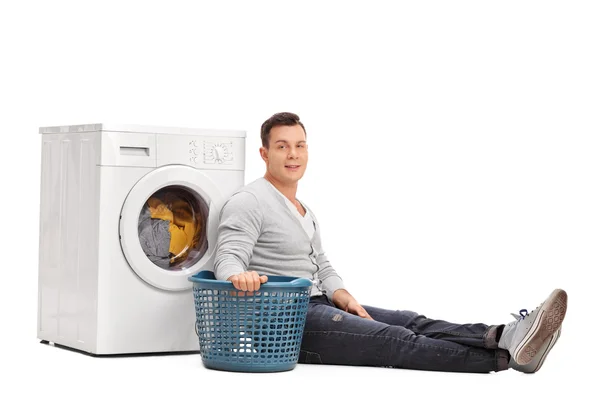 Young man sitting by a washing machine — Stock Photo, Image