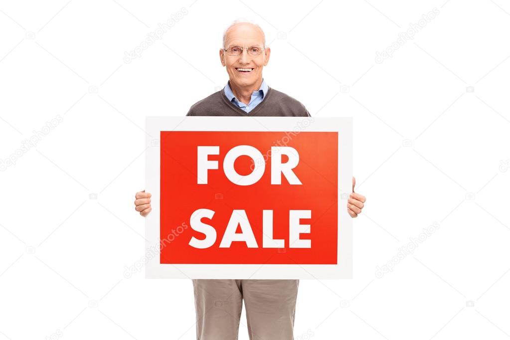 Senior gentleman holding a for sale sign 