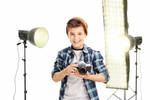 Vrolijke jongen die houden van een camera in een studio — Stockfoto