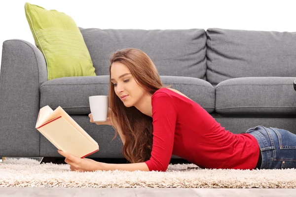 Jeune femme par terre lisant un livre — Photo