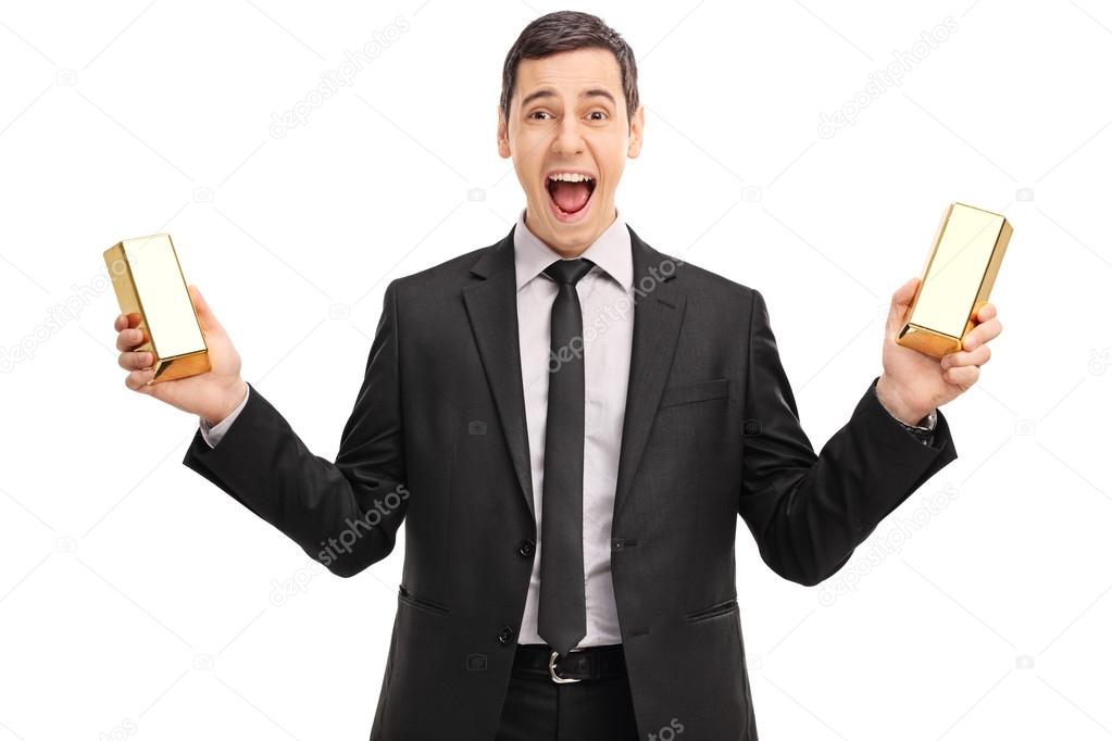 Excited businessman holding gold bars