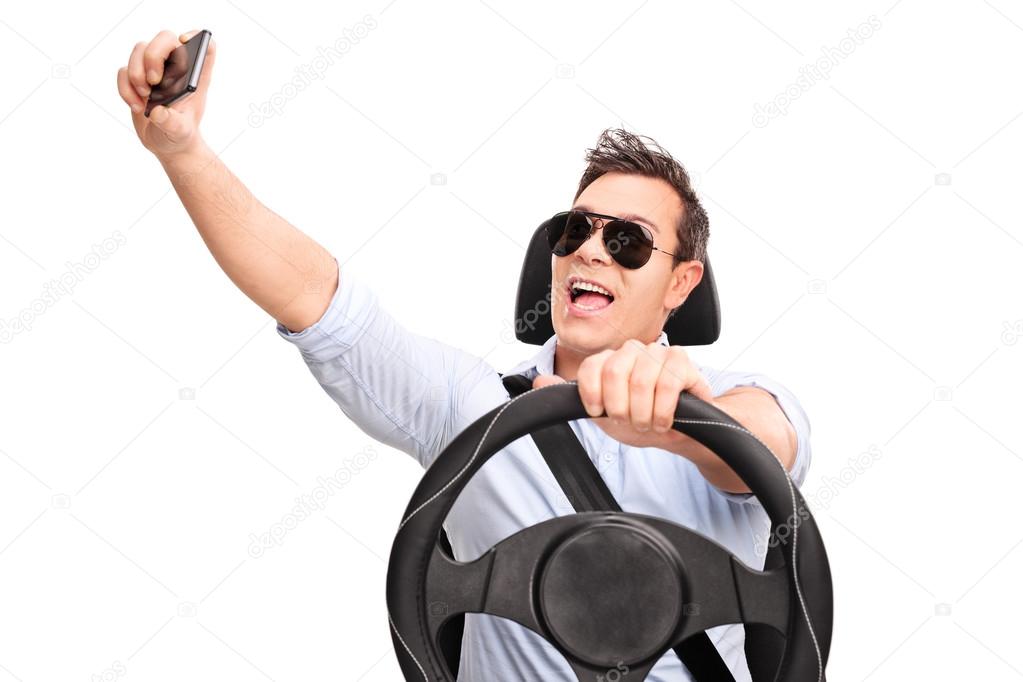 Young man driving and taking a selfie 