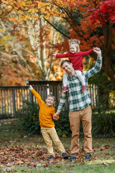 Tata i dwójka dzieci spacerują po jesiennym parku. Szczęśliwa rodzina.. — Zdjęcie stockowe