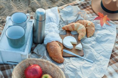 Göl kenarında güzel bir piknik. Sıcak çay, termos, battaniye, kruvasan, peynir, meyve, balkabağı. Güzel bir sonbahar dekoru. Düş.