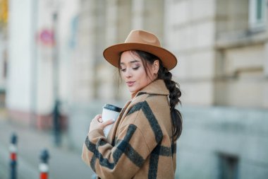 Yakın plan, şapkalı, kahve içen güzel bir kadın Avrupa 'da yürüyor.