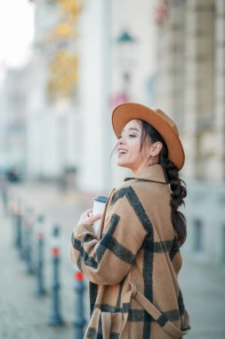 Yakın plan, şapkalı, kahve içen güzel bir kadın Avrupa 'da yürüyor.