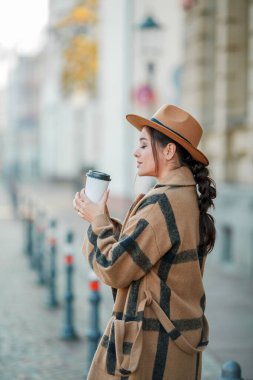 Yakın plan, şapkalı, kahve içen güzel bir kadın Avrupa 'da yürüyor.