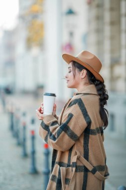 Yakın plan, şapkalı, kahve içen güzel bir kadın Avrupa 'da yürüyor.