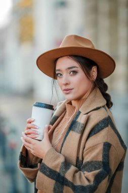 Yakın plan, şapkalı, kahve içen güzel bir kadın Avrupa 'da yürüyor.